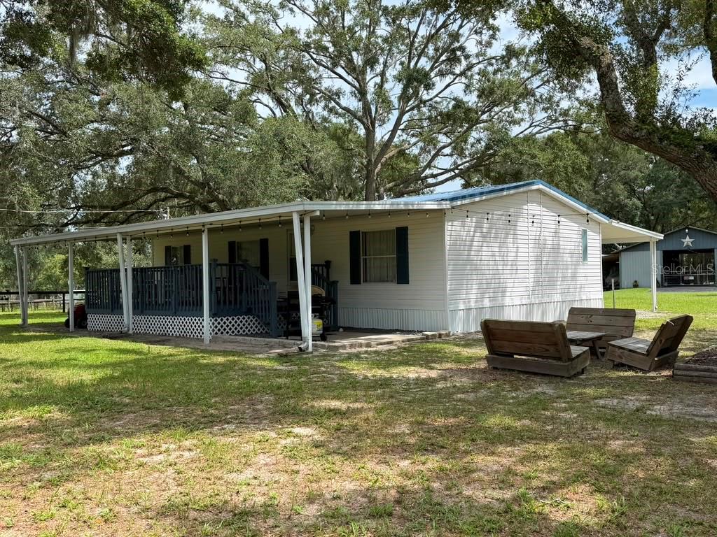 A white mobile home features a large covered wooden deck and a grassy yard — 7320 SW 22ND STREET, OCALA, FL