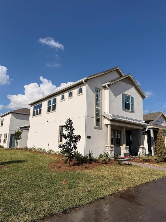 A two-story house with a light-colored stucco exterior and a stone-accented front porch — 10374 PEARSON AVE, ORLANDO, FL