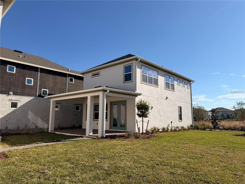 A two-story house with a covered patio, light-colored stucco exterior, and a grassy backyard — 10374 PEARSON AVE, ORLANDO, FL