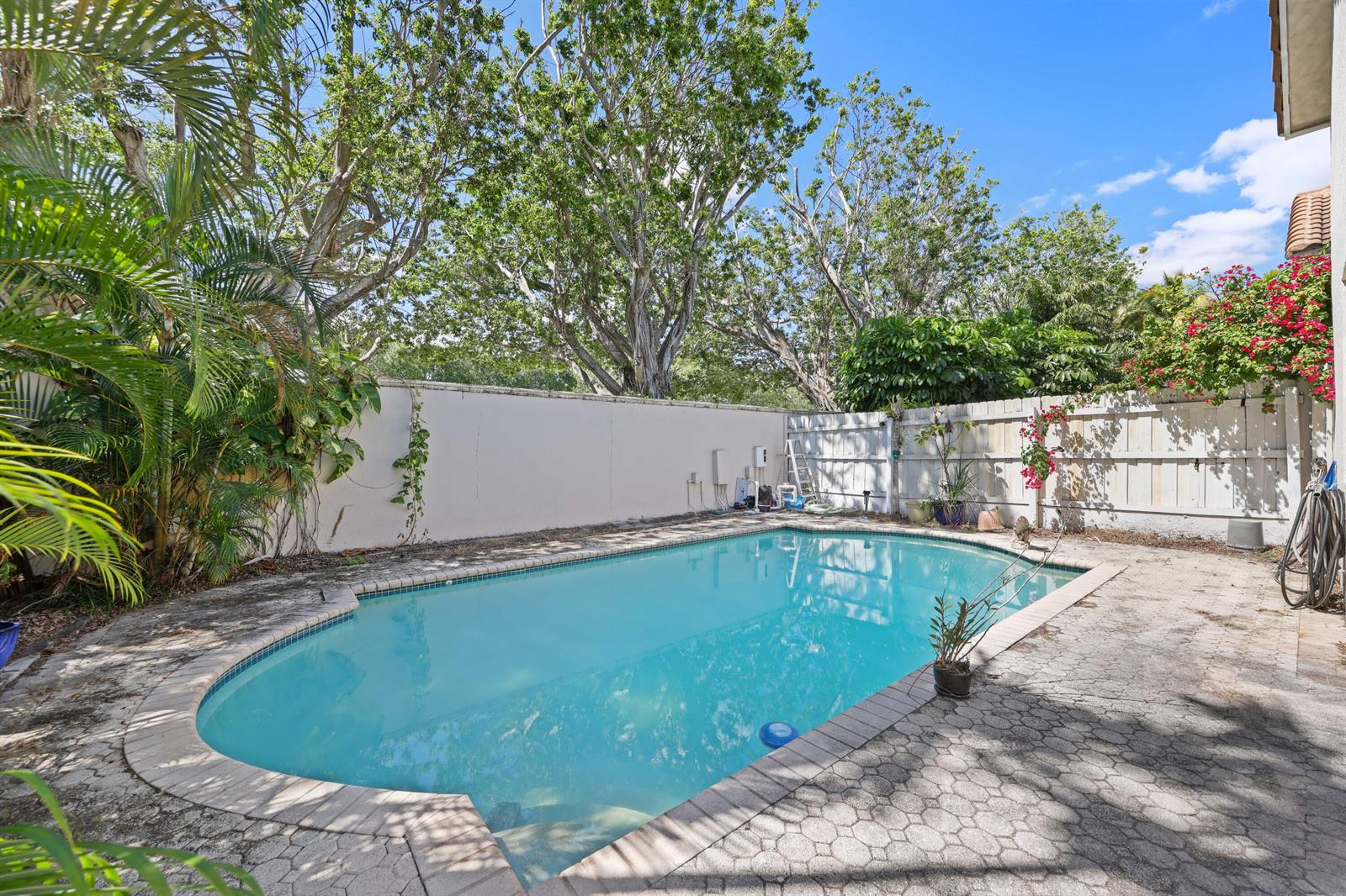 A backyard swimming pool with a paved deck, surrounded by a fence and mature trees — 2502 NW 66th Drive, Boca Raton FL 33496, BOCA RATON, FL