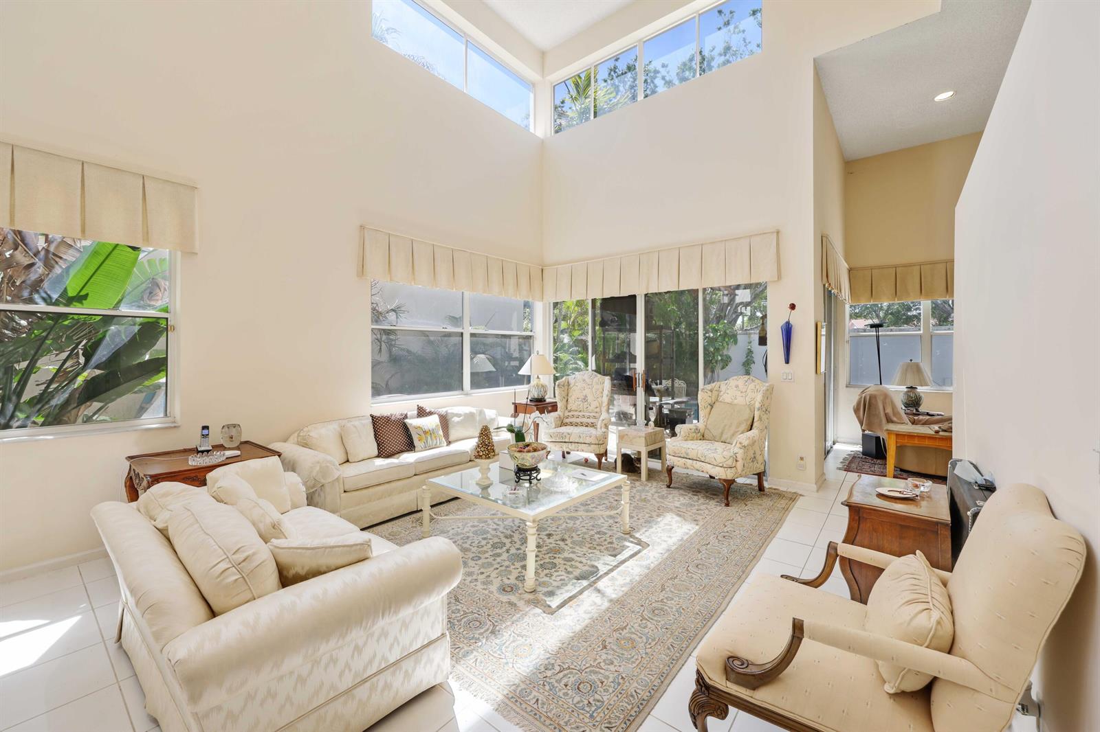 A bright living room features high ceilings, large windows, tile floors, and traditional upholstered furniture — 2502 NW 66th Drive, Boca Raton FL 33496, BOCA RATON, FL
