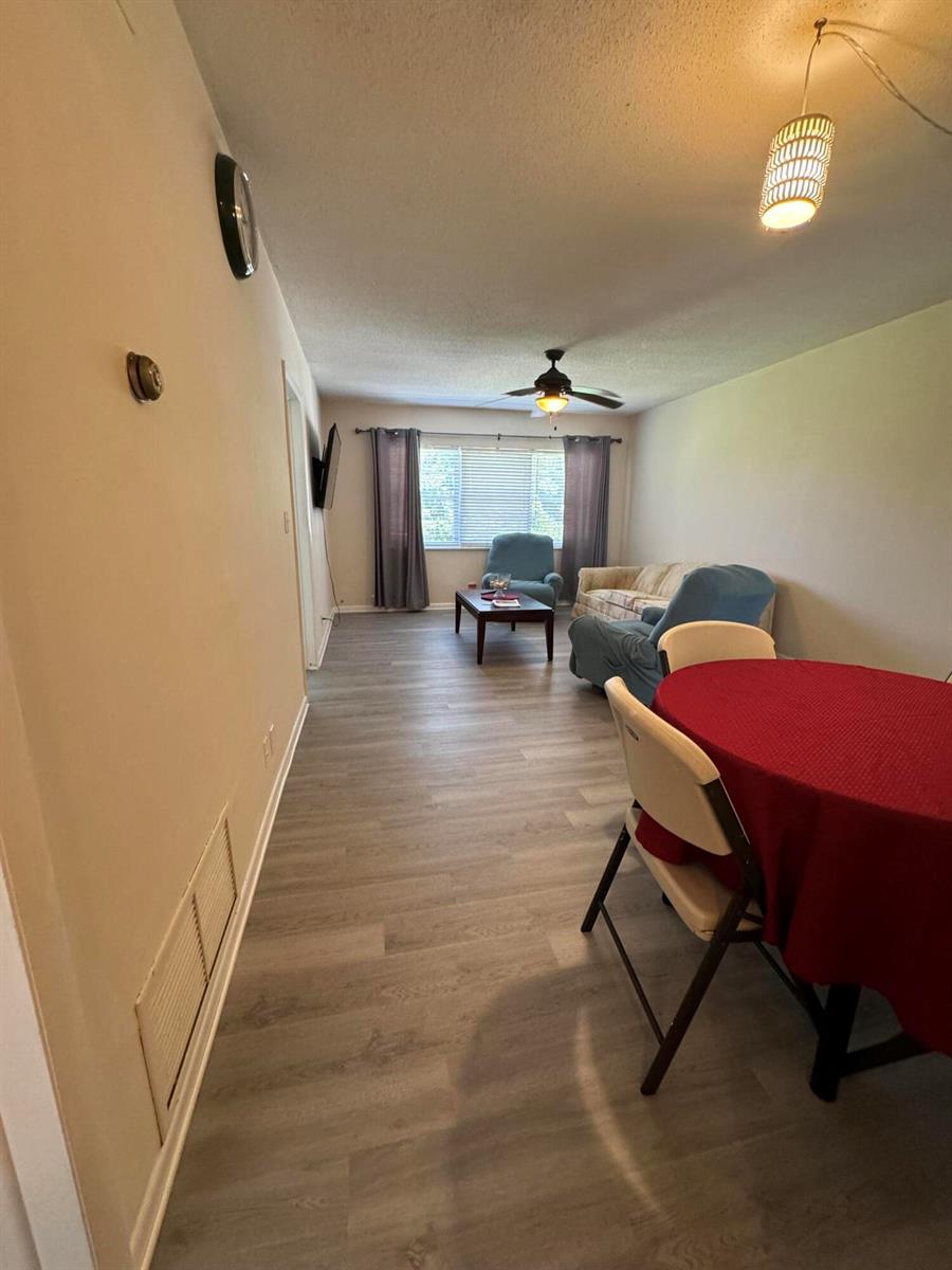 A living room and dining area with light wood-look flooring and a red tablecloth — 2851 E Golf Boulevard # 206, Pompano Beach FL 33064, POMPANO BEACH, FL