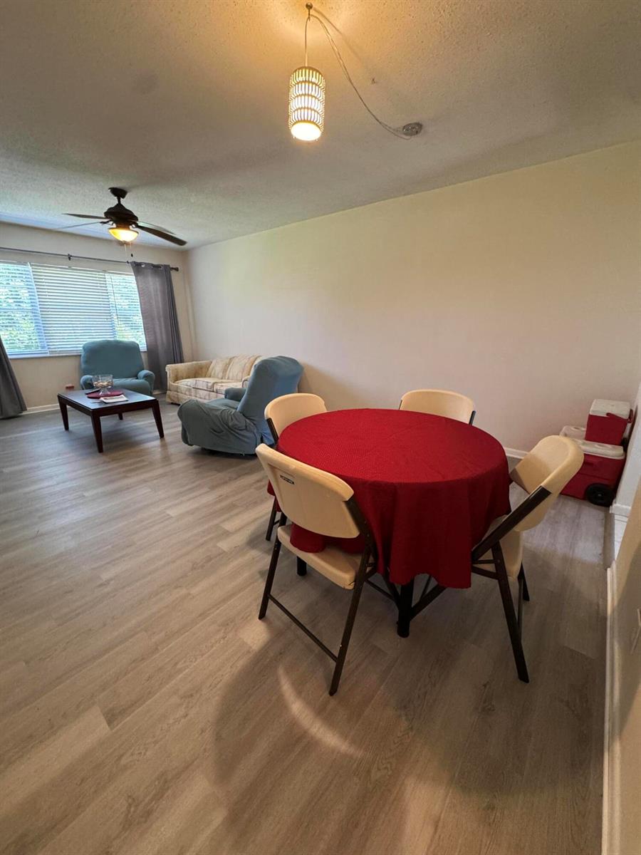 A living and dining area with light wood-look flooring, a ceiling fan, and a round table — 2851 E Golf Boulevard # 206, Pompano Beach FL 33064, POMPANO BEACH, FL