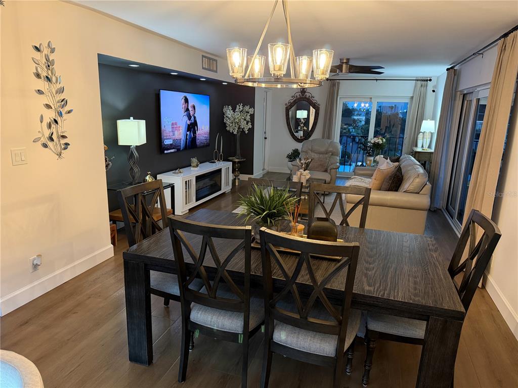 A dining area with a dark wood table opens into a living room with a television — 1480 GULF BOULEVARD UNIT 309, CLEARWATER BEACH, FL