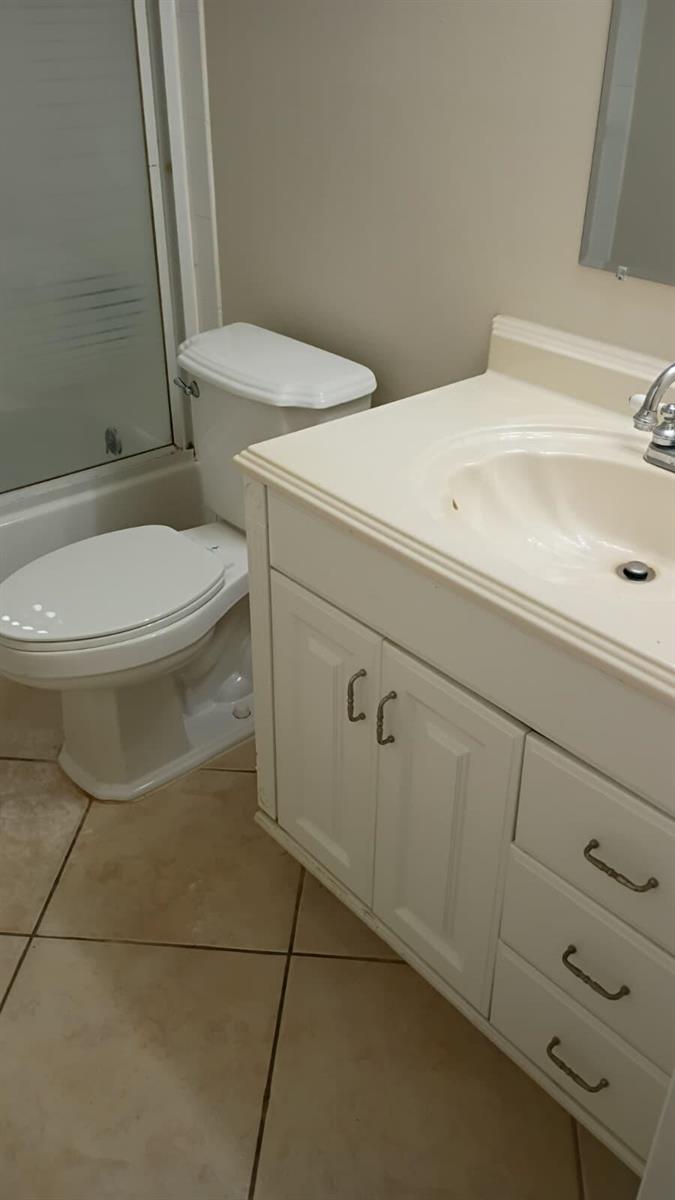 A bathroom features a white vanity with a sink, a toilet, and tiled flooring — 1205 S Flagler Avenue # 405, Pompano Beach FL 33060, POMPANO BEACH, FL