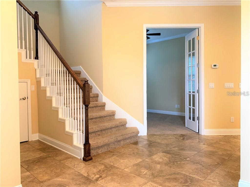 An interior view of a foyer with tiled floors, a carpeted staircase, and French doors — 8650 TAVISTOCK LAKES BOULEVARD, ORLANDO, FL