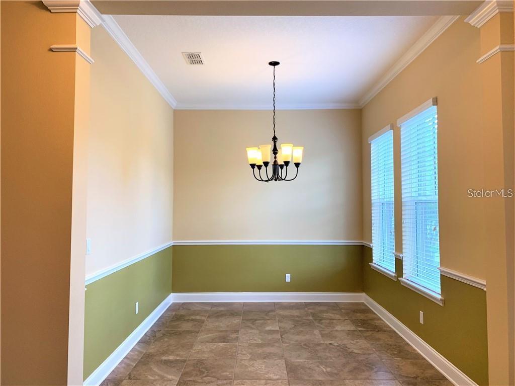 A dining room features tile flooring, two-tone walls with chair rail molding, and a chandelier — 8650 TAVISTOCK LAKES BOULEVARD, ORLANDO, FL
