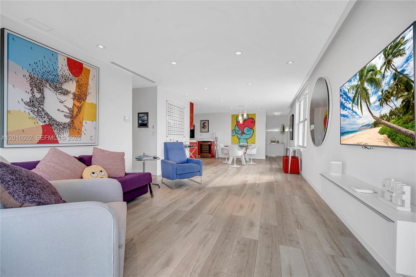 A bright living and dining area features light wood floors, colorful artwork, and modern furniture — 3 Island Ave # 08I, Miami Beach FL 33139, MIAMI BEACH, FL