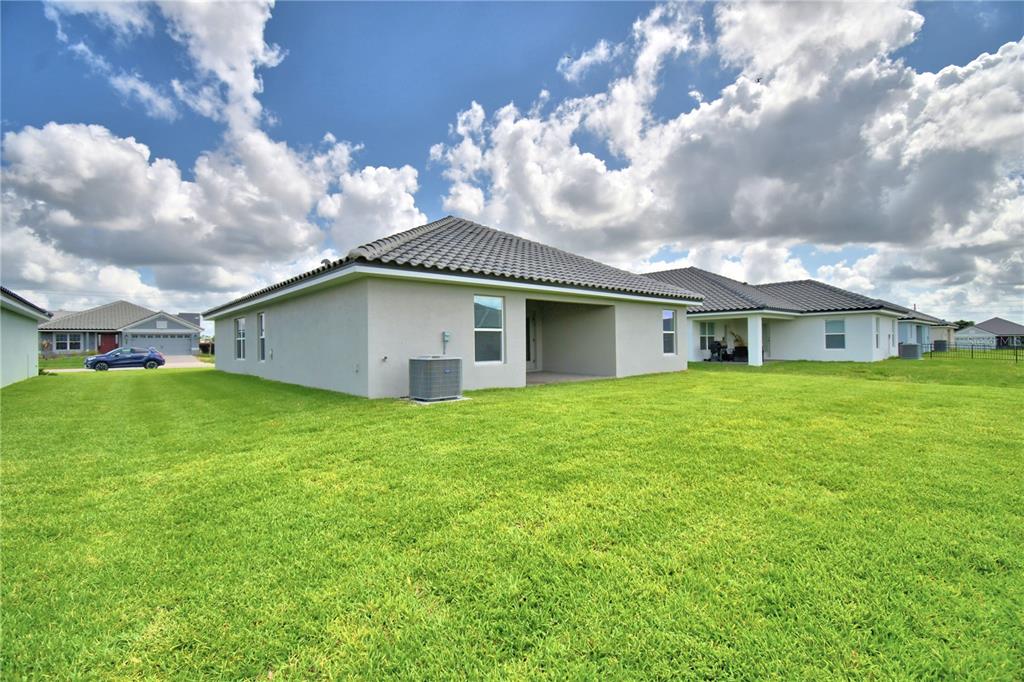 The exterior rear view of a single-story house with a lawn and tiled roof — 4651 GRANDVIEW GLEN DRIVE, AUBURNDALE, FL