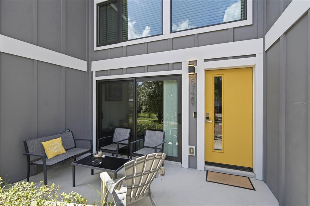 A patio features a yellow front door, sliding glass doors, and outdoor furniture — 5729 75TH TERRACE N, PINELLAS PARK, FL