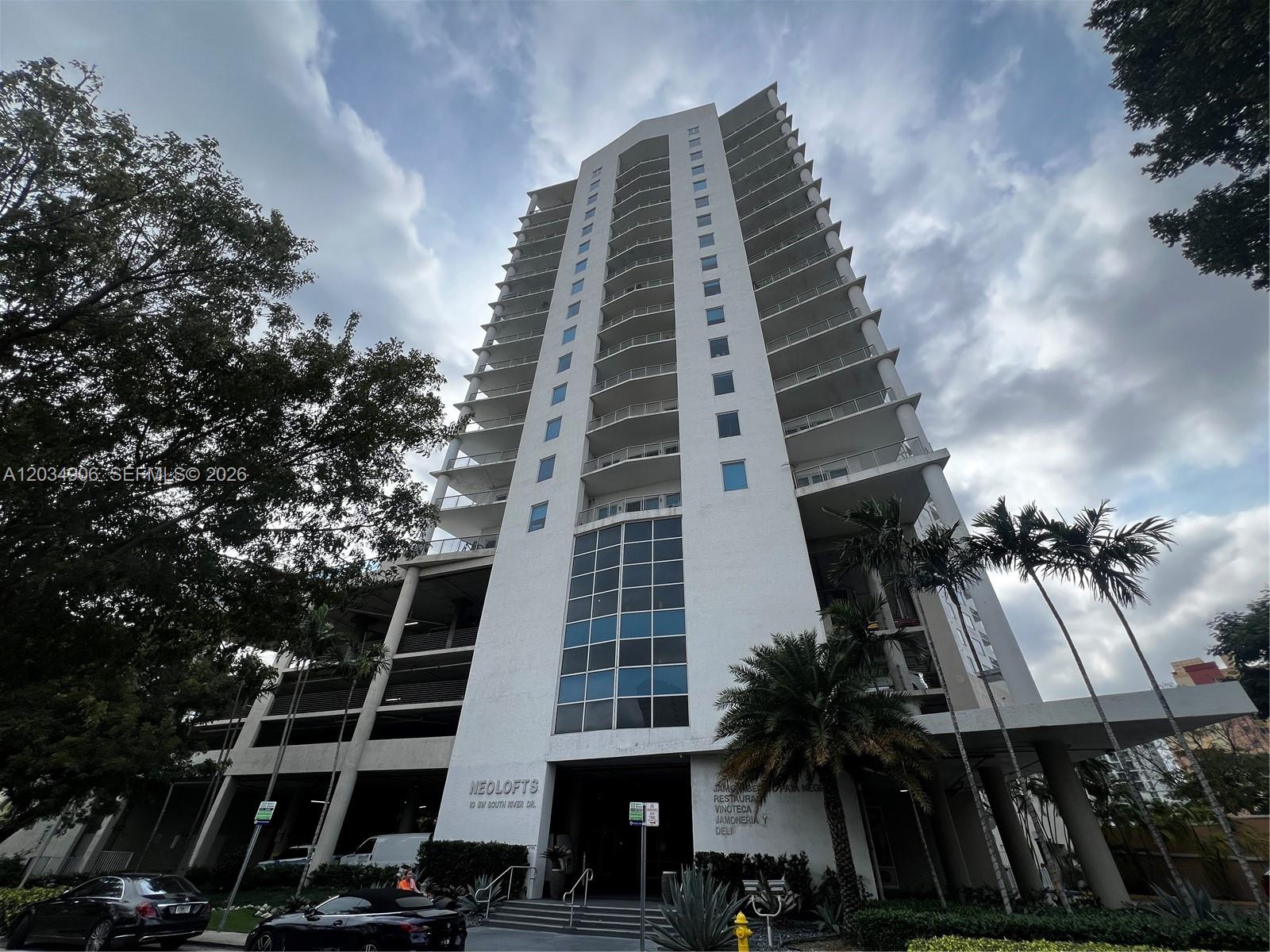 A low-angle view of the Neolofts high-rise building exterior under a cloudy sky — 10 SW South River Dr # 812, Miami FL 33130, MIAMI, FL