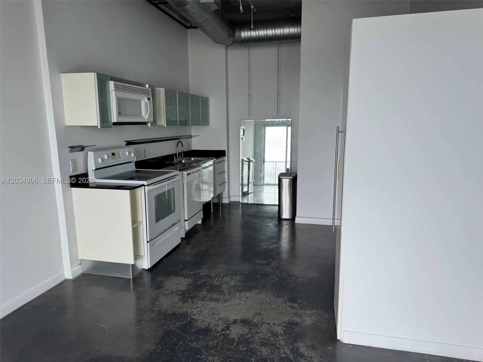 A kitchen with white cabinets, stainless steel appliances, and dark concrete flooring — 10 SW South River Dr # 812, Miami FL 33130, MIAMI, FL