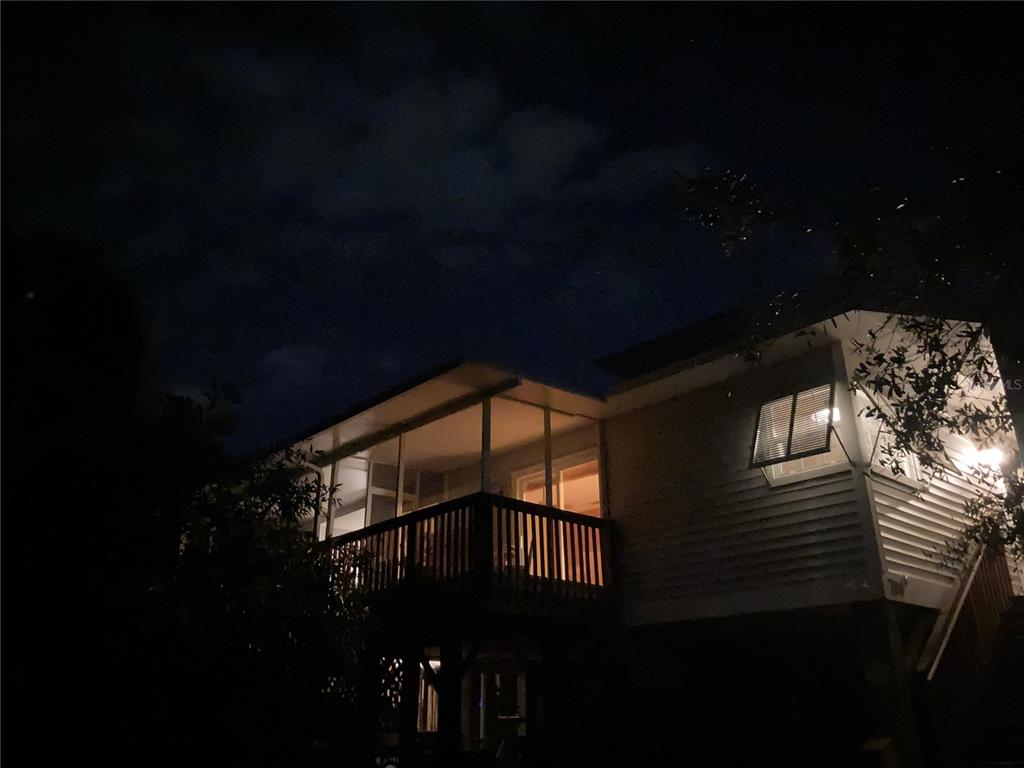 A two-story house exterior at night featuring a screened-in porch and a wooden deck — 700 YALE STREET, ENGLEWOOD, FL