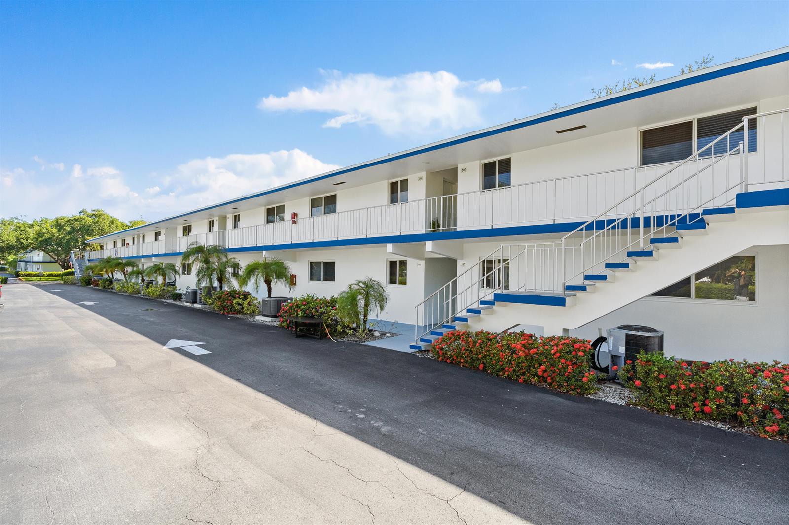 A two-story apartment building features white exterior walls, blue trim, and an outdoor staircase — 4 Westwood Avenue # 204, Jupiter FL 33469, JUPITER, FL