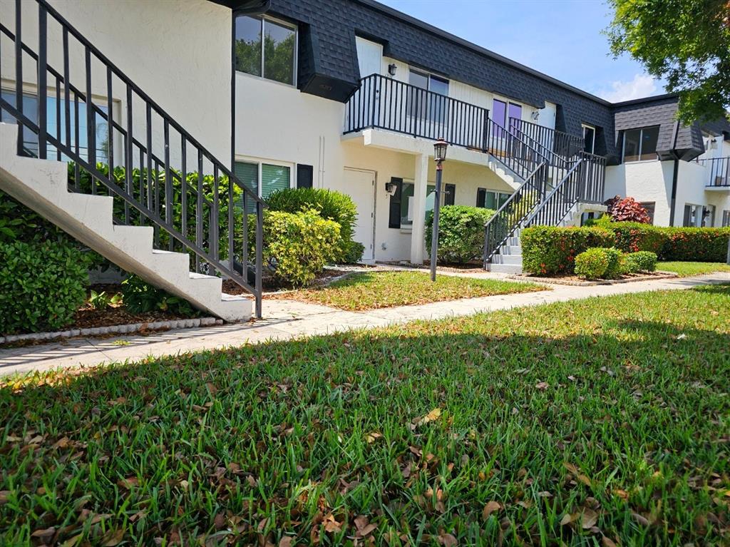 Exterior view of a two-story apartment building with white stucco walls and black railings — 4722 SE 1ST PLACE UNIT 5, CAPE CORAL, FL