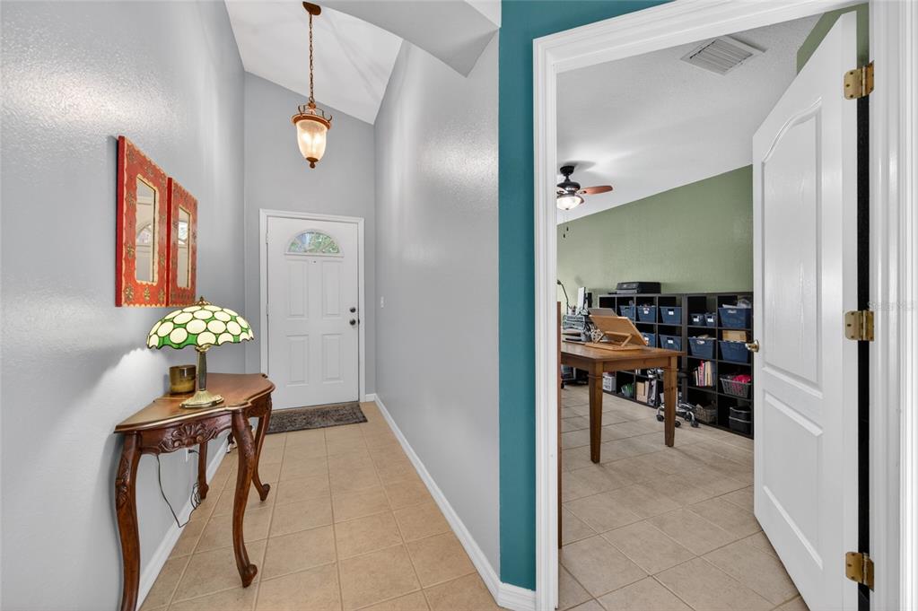 A tiled entryway features a small wooden table, a stained-glass lamp, and a doorway — 18 OAK VILLAGE DRIVE, ORMOND BEACH, FL