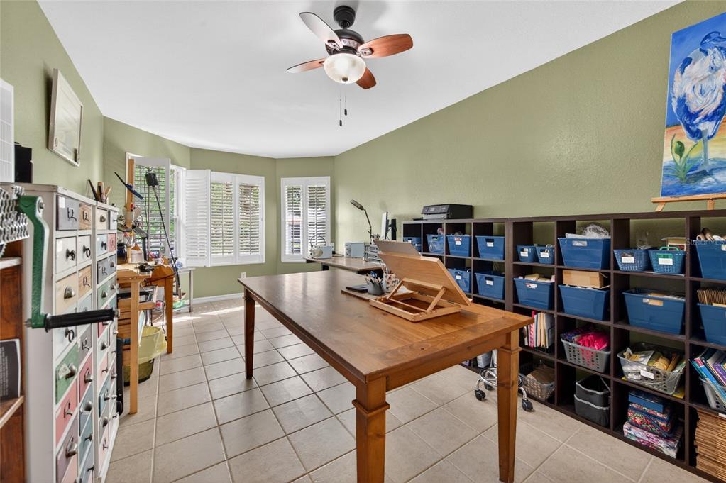 A craft room with a large wooden table, storage cubbies, and light green walls — 18 OAK VILLAGE DRIVE, ORMOND BEACH, FL