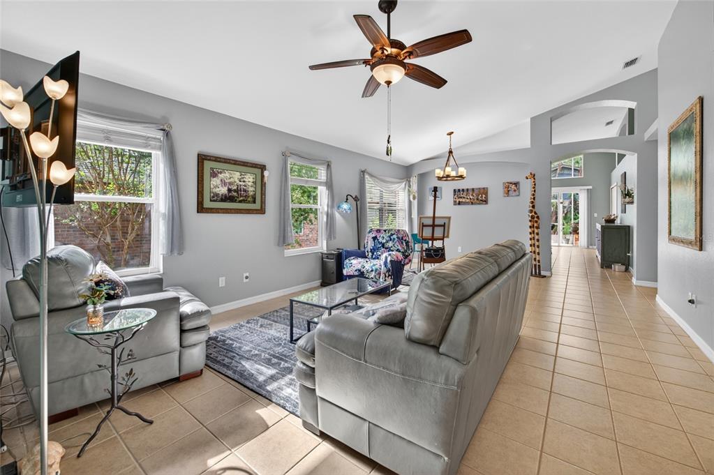 A living room with gray walls, tile flooring, a ceiling fan, and gray leather furniture — 18 OAK VILLAGE DRIVE, ORMOND BEACH, FL