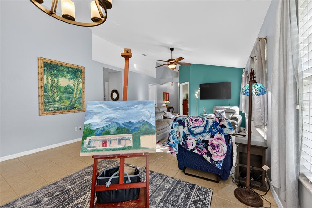 A living room features a painting on an easel, tile flooring, and a teal accent wall — 18 OAK VILLAGE DRIVE, ORMOND BEACH, FL