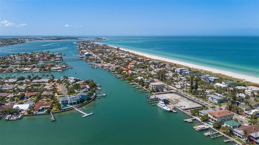 An aerial view shows a coastal neighborhood with houses along a canal and a beach — 2505 PASS A GRILLE WAY, ST PETE BEACH, FL