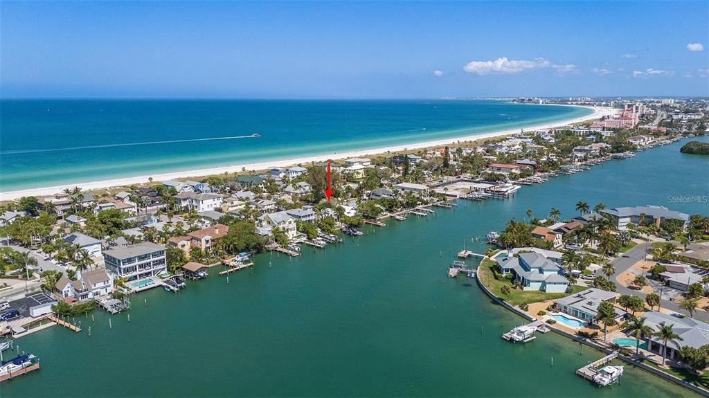 An aerial view shows a coastal neighborhood with houses along a canal and beach — 2505 PASS A GRILLE WAY, ST PETE BEACH, FL