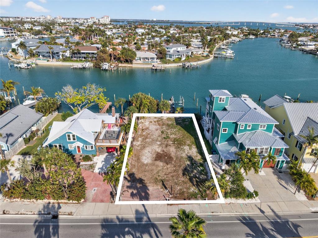 An aerial view shows a vacant waterfront lot situated between two houses — 2505 PASS A GRILLE WAY, ST PETE BEACH, FL