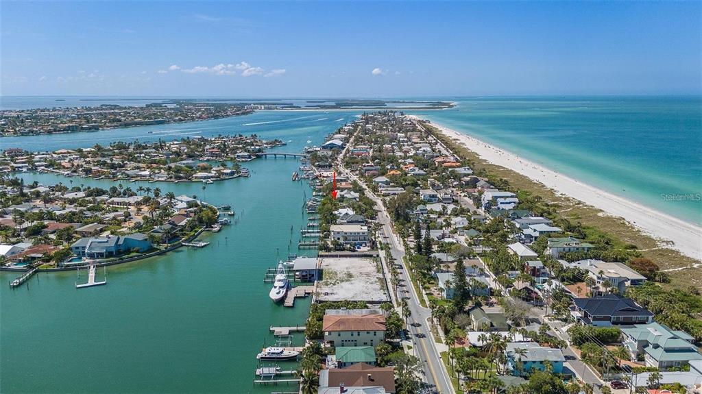 An aerial view shows a coastal neighborhood with houses, a canal, and a sandy beach — 2505 PASS A GRILLE WAY, ST PETE BEACH, FL
