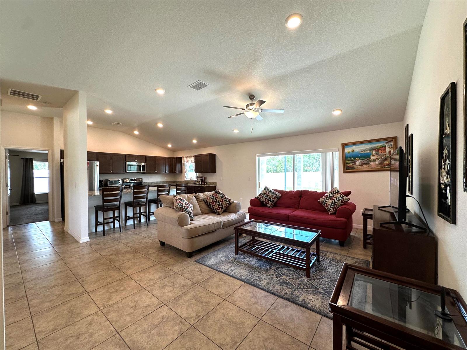An open-concept living room and kitchen featuring tile floors, dark cabinetry, and two sofas — 15211 SW 65th Ter Road, Ocala FL 34473, OCALA, FL