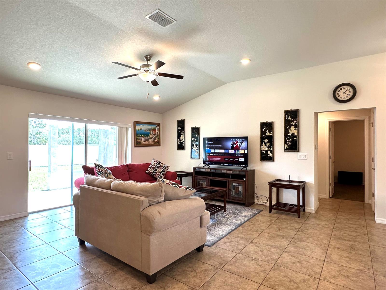 A living room features a beige sofa, a red couch, a television, and tile flooring — 15211 SW 65th Ter Road, Ocala FL 34473, OCALA, FL