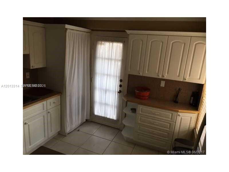 A kitchen features white cabinets, a tiled floor, and a glass-paned door with curtains — 10794 N Kendall Dr # B23, Miami FL 33176, MIAMI, FL