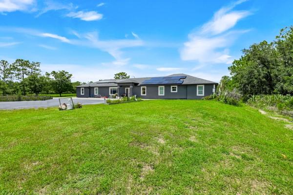 A single-story gray house with solar panels sits on a large, grassy lot — 19327 RALSTON ST, ORLANDO, FL