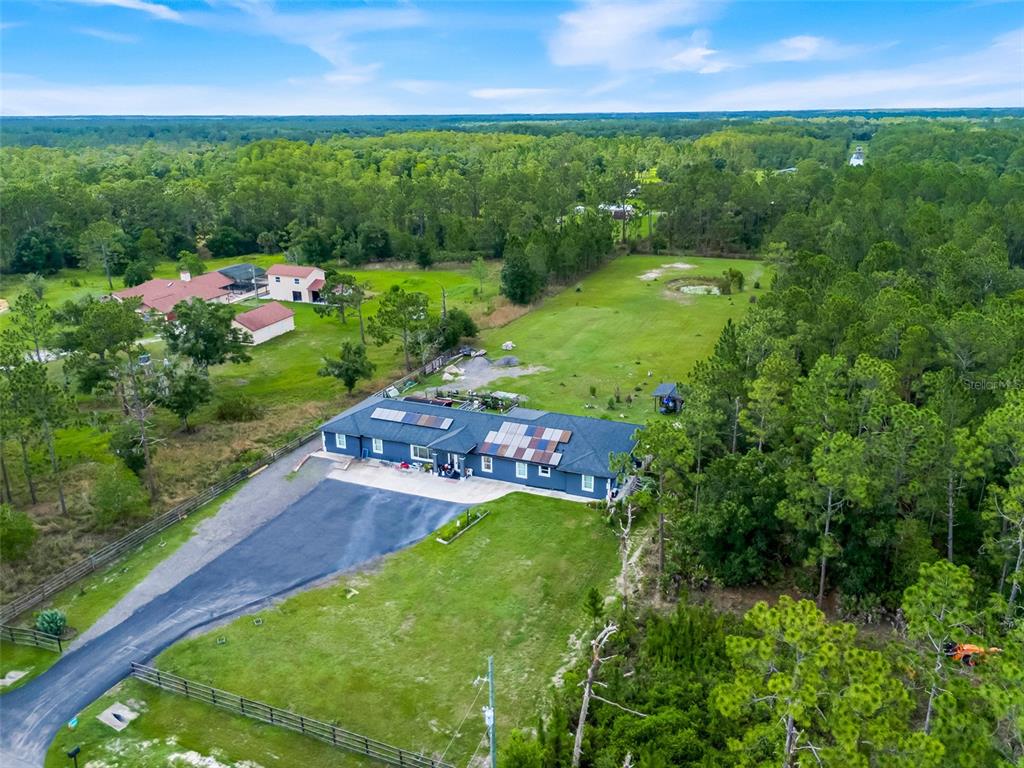An aerial view shows a dark blue house with solar panels on a large, wooded lot — 19327 RALSTON ST, ORLANDO, FL