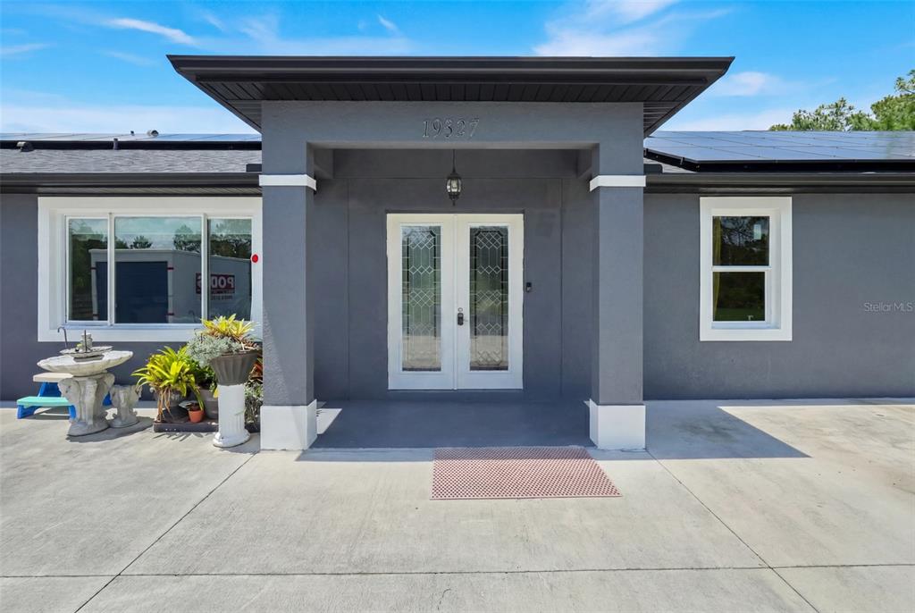 The exterior of a gray house features a covered entryway with double glass-paneled doors — 19327 RALSTON ST, ORLANDO, FL
