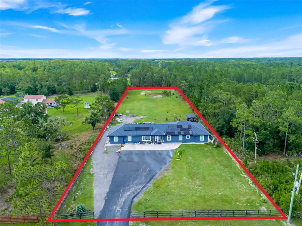 An aerial view shows a single-story blue house on a large, fenced, grassy lot — 19327 RALSTON ST, ORLANDO, FL