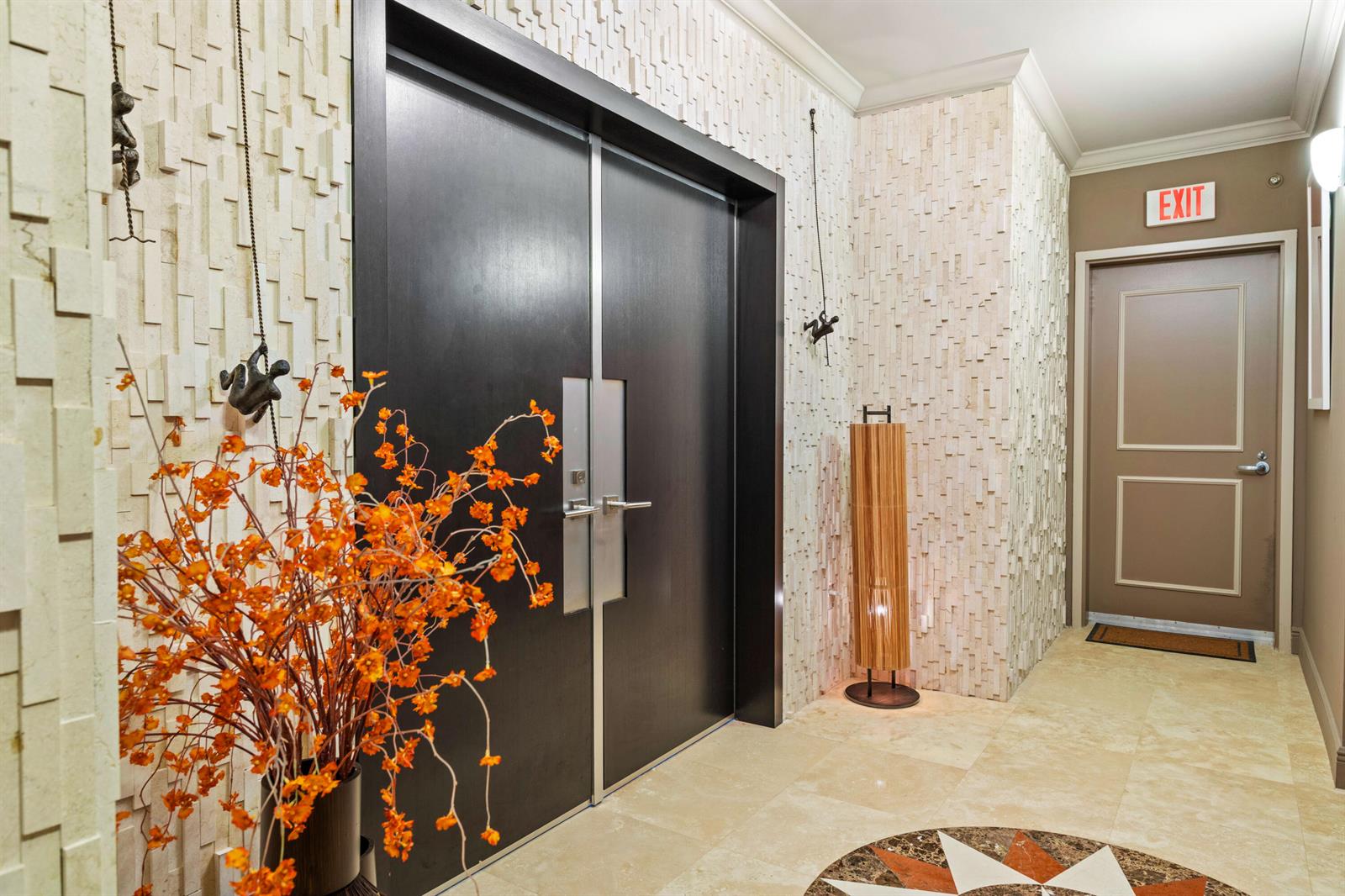 A modern entryway features double dark wood doors, textured stone walls, and a decorative floor inlay — 3101 S Ocean Drive # 3105, Hollywood FL 33019, HOLLYWOOD, FL