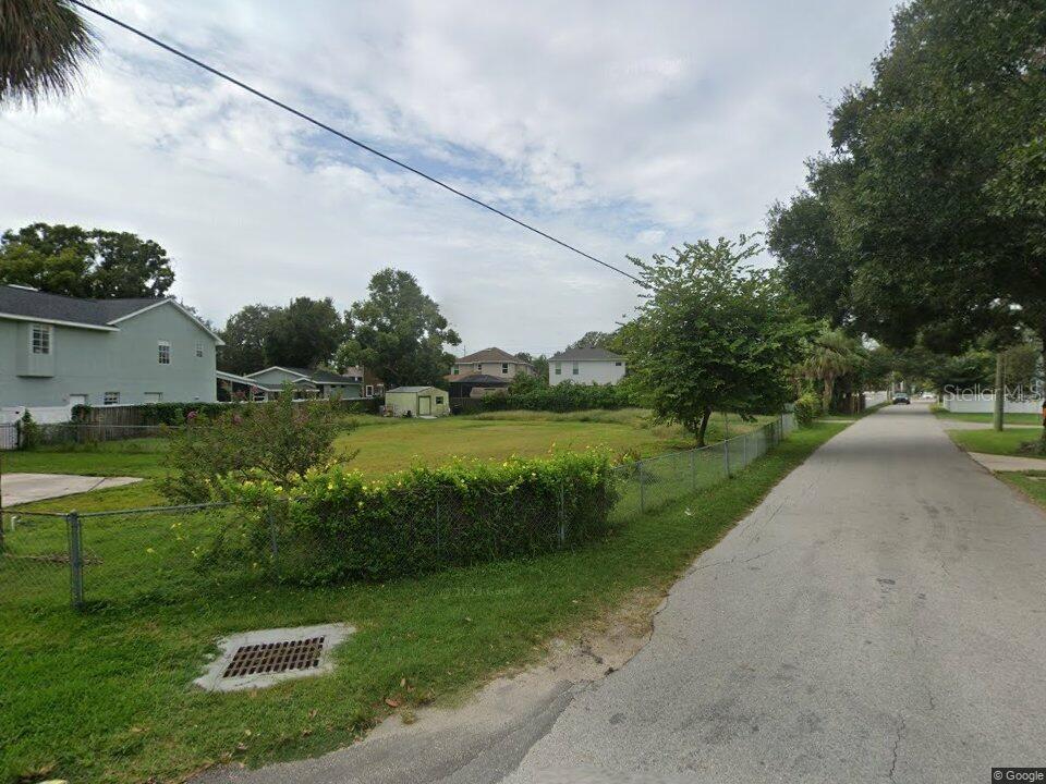 A vacant, grassy residential lot sits between houses along a paved street — 5801 S 2ND STREET, TAMPA, FL