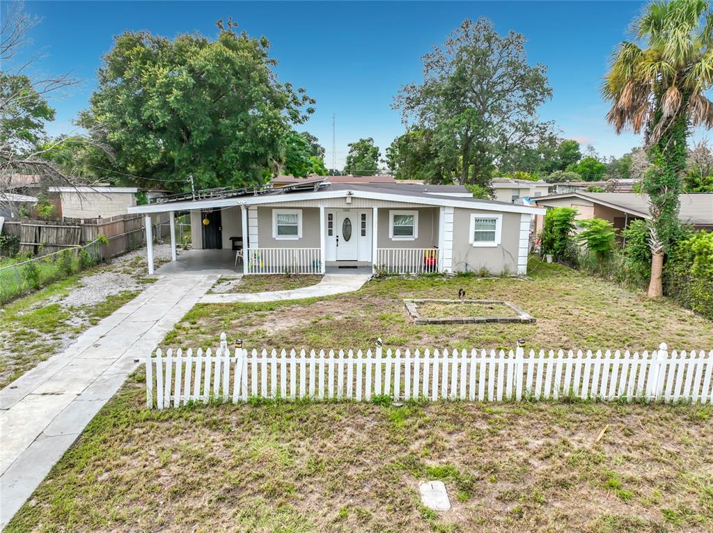 A single-story house with a white picket fence, a concrete driveway, and a covered porch — 5602 ASTORIA PLACE, ORLANDO, FL