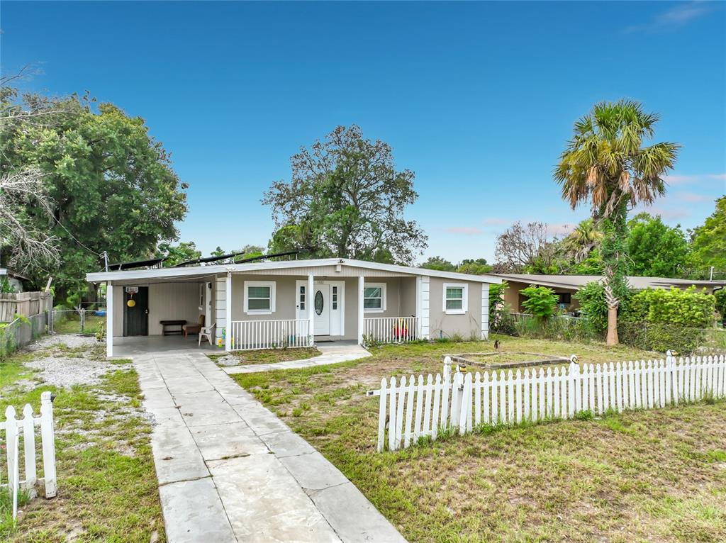 A single-story house with a white picket fence, a concrete driveway, and a covered carport — 5602 ASTORIA PLACE, ORLANDO, FL