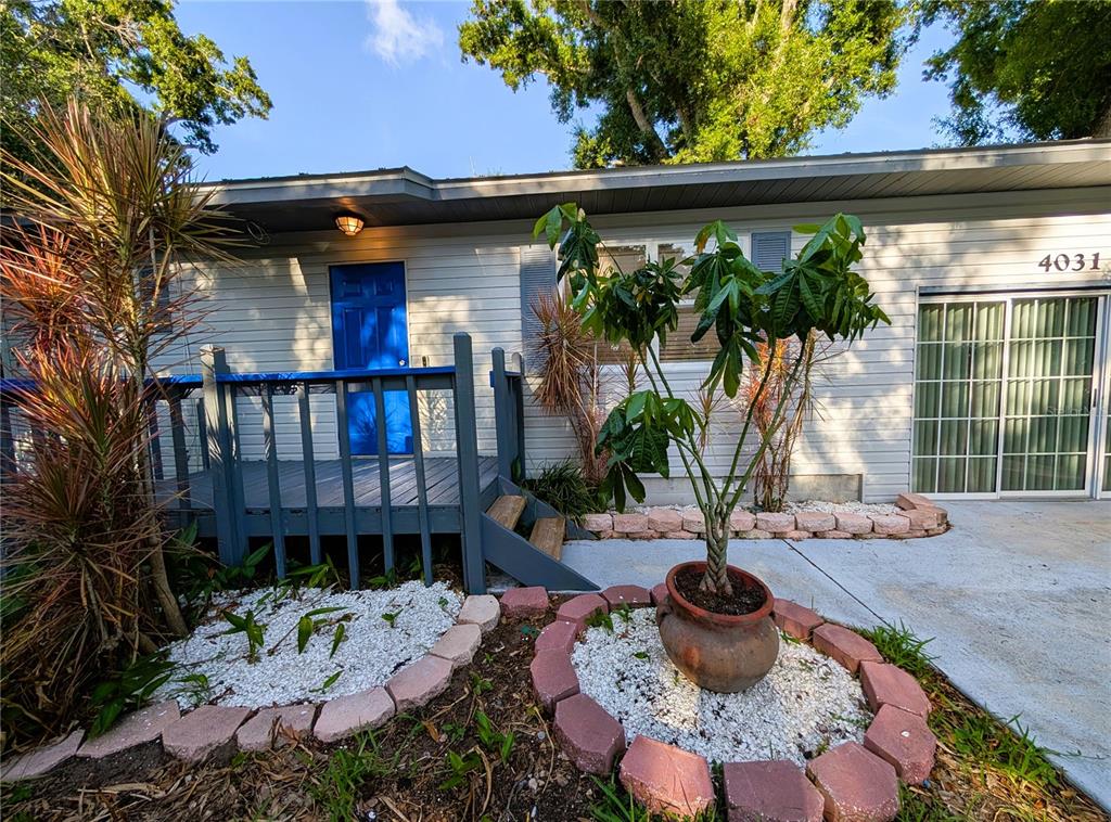 A house exterior features a blue front door, a wooden deck, and a potted plant — 4031 IOLA DRIVE, SARASOTA, FL