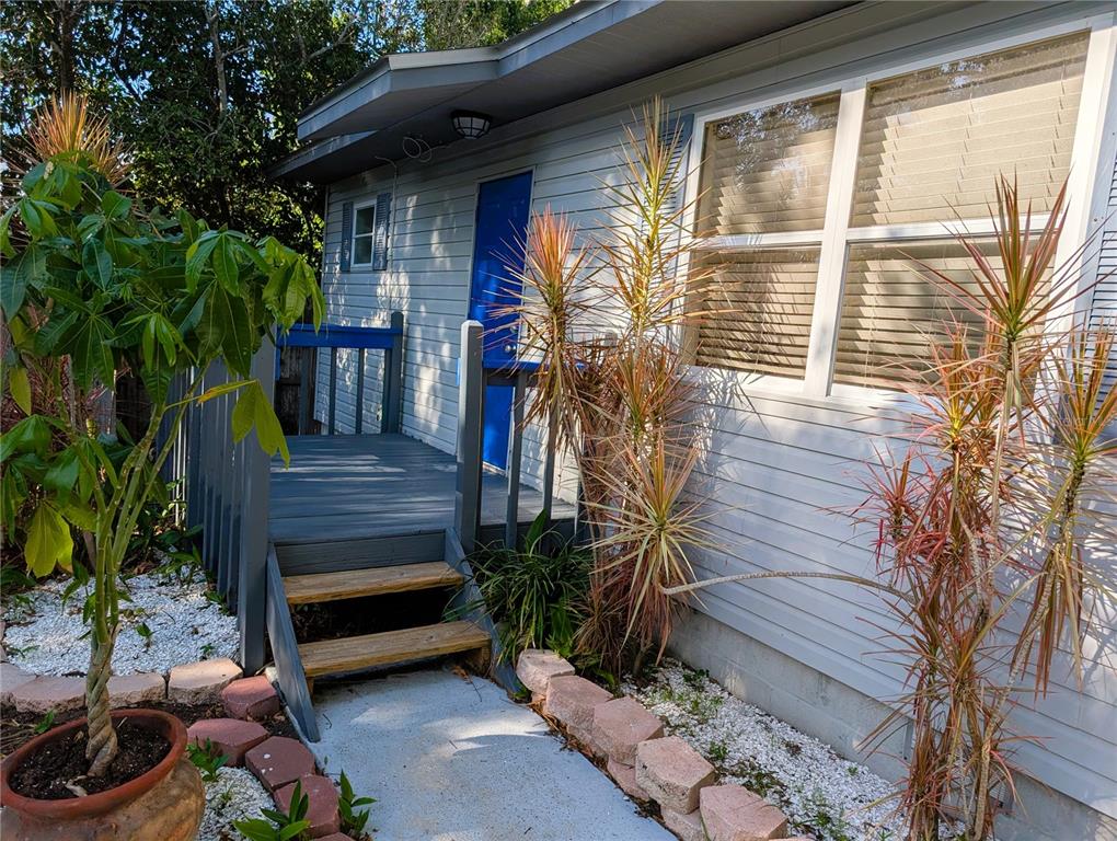A small wooden deck with blue railings leads to a bright blue door on a house — 4031 IOLA DRIVE, SARASOTA, FL