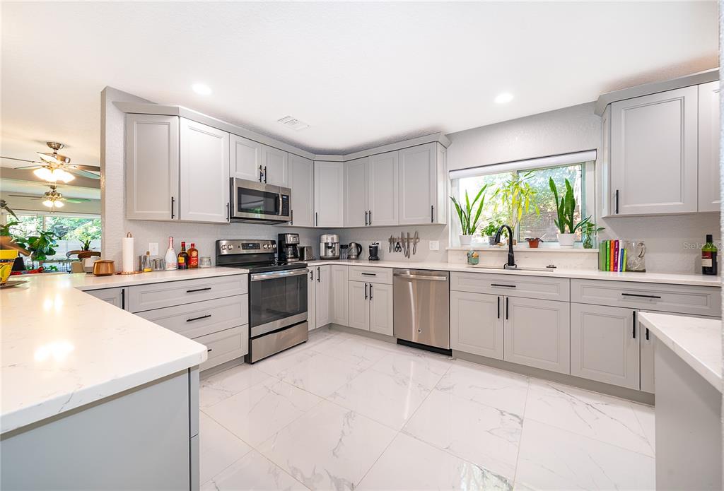 A living room with a white sofa, floral rug, and an open kitchen with bar seating — 502 OAK LANE, MAITLAND, FL