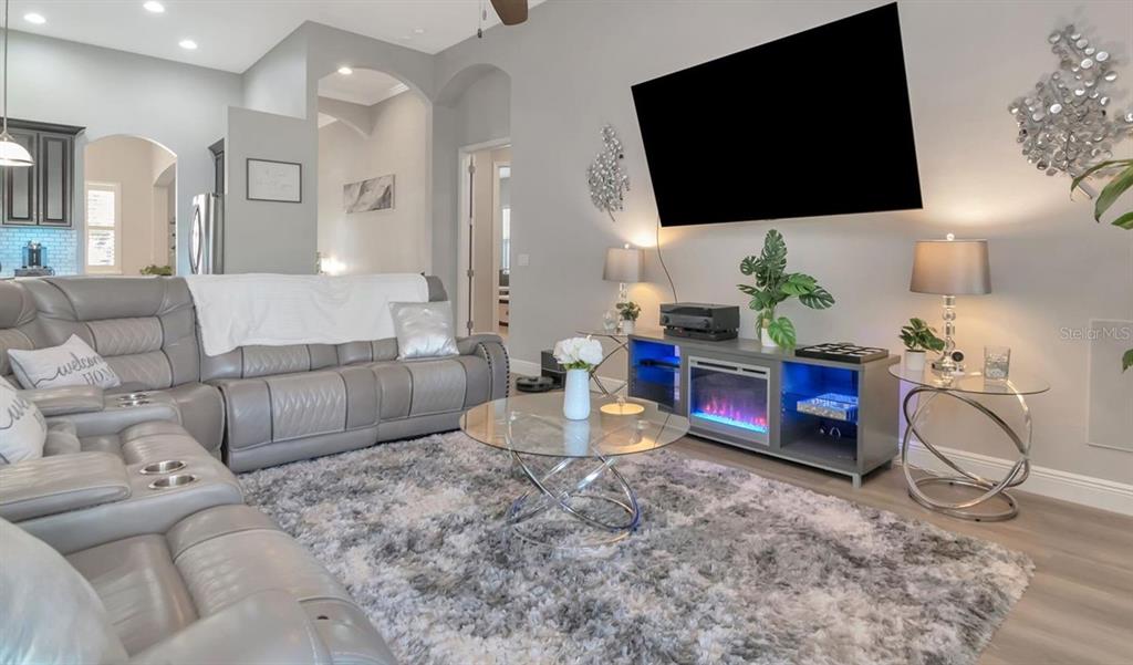 A living room features a grey sectional sofa, a glass coffee table, and a fireplace console — 19419 AUTUMN CHASE COURT, LAND O LAKES, FL