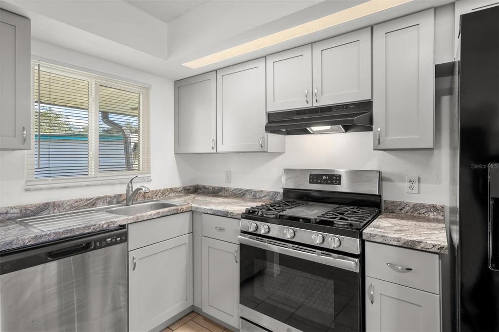 A kitchen features light gray cabinets, stainless steel appliances, and a patterned stone countertop — 831 ORCHID SPRINGS DRIVE UNIT #831, WINTER HAVEN, FL