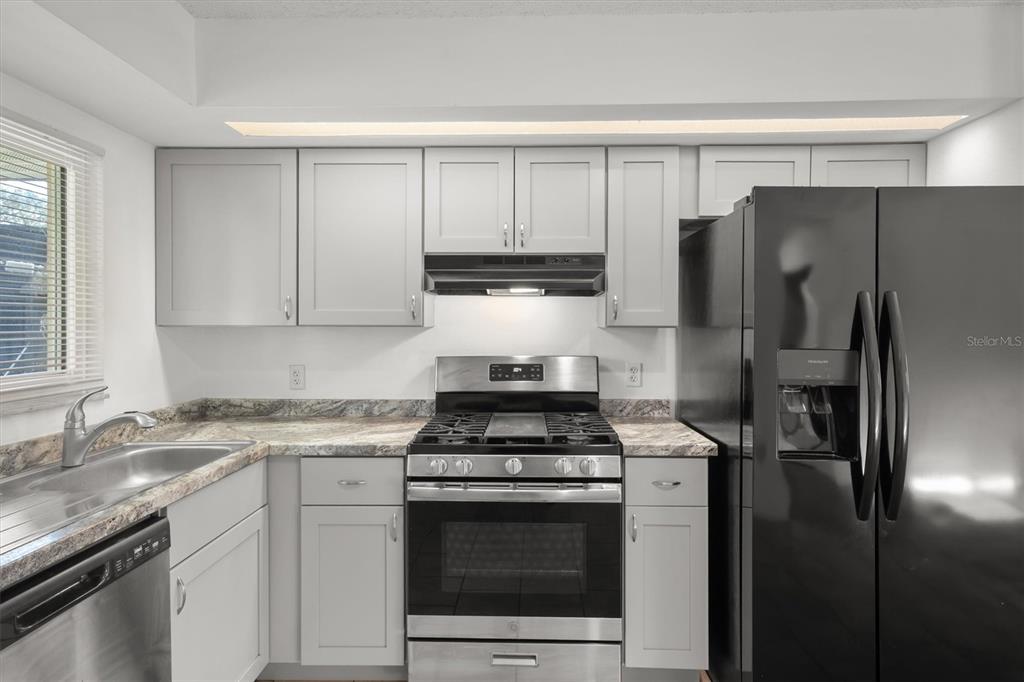 A kitchen features gray cabinets, stainless steel appliances, a black refrigerator, and granite-look countertops — 831 ORCHID SPRINGS DRIVE UNIT #831, WINTER HAVEN, FL