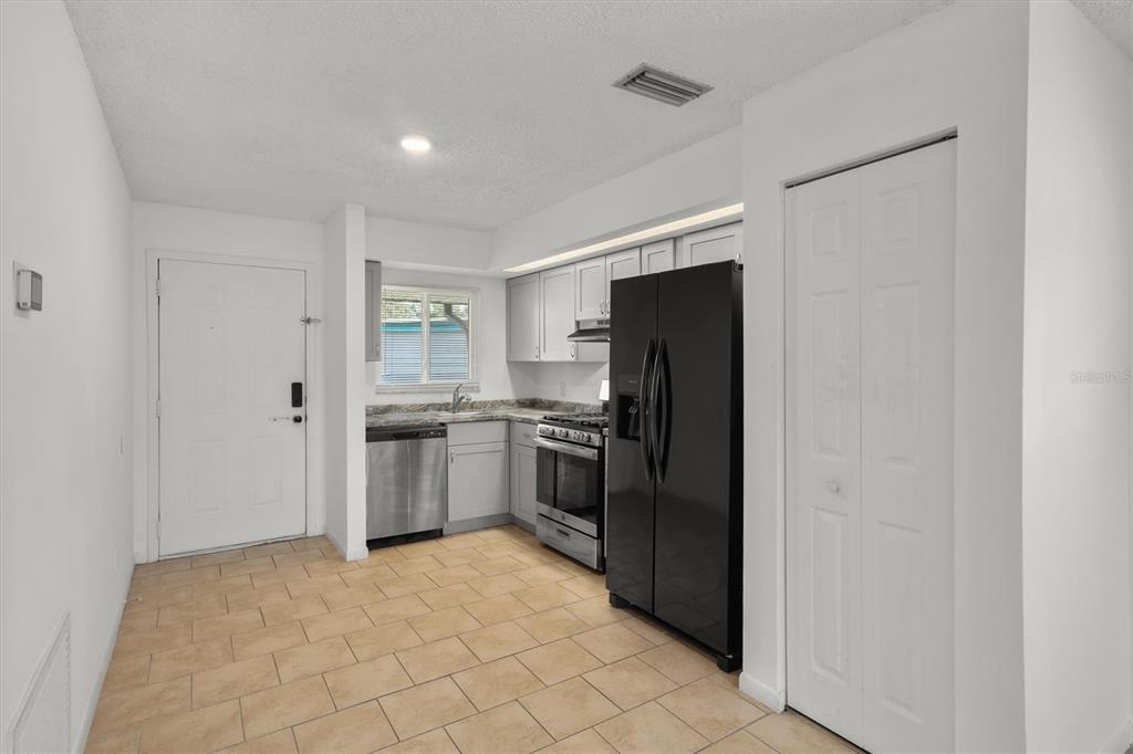 A kitchen features light gray cabinets, stainless steel appliances, a black refrigerator, and tile flooring — 831 ORCHID SPRINGS DRIVE UNIT #831, WINTER HAVEN, FL