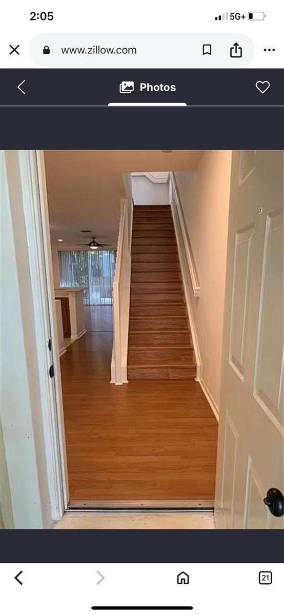 An entryway with wood-look flooring leads to a staircase and an open living area beyond — 9772 Porta Leona Lane, Boynton Beach FL 33472, BOYNTON BEACH, FL