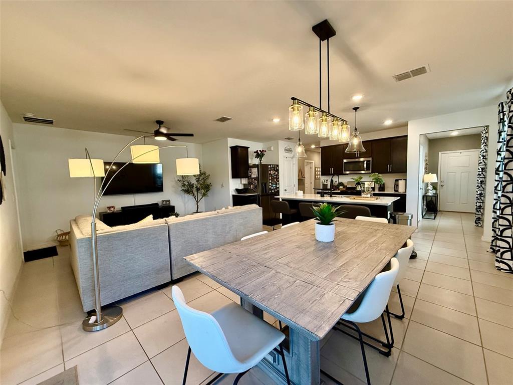 An open-concept living and dining area features a large wooden table, sectional sofa, and kitchen — 20873 DRAKE ELM DRIVE, LAND O LAKES, FL