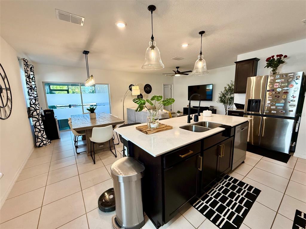 A kitchen with a dark island, white countertops, and stainless steel appliances opens to a dining area — 20873 DRAKE ELM DRIVE, LAND O LAKES, FL
