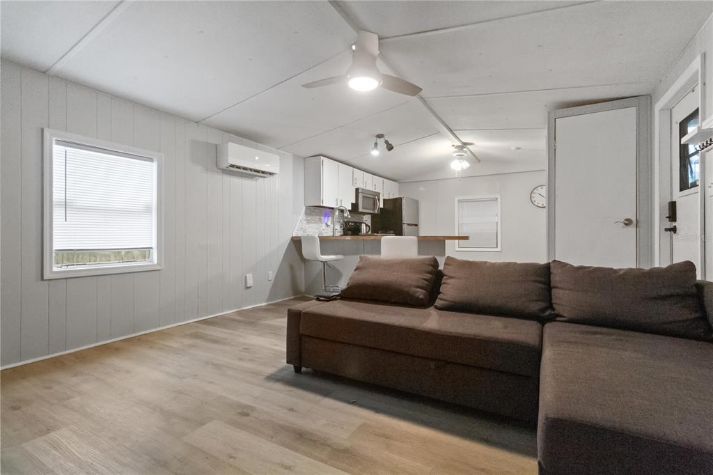 A living room with a brown sectional sofa, light wood floors, and an open kitchen — 11301 EDISON AVENUE, NEW PORT RICHEY, FL
