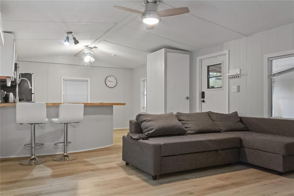 A living room with a gray sectional sofa, a breakfast bar, and light wood flooring — 11301 EDISON AVENUE, NEW PORT RICHEY, FL